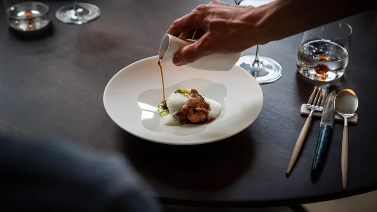 Een gerecht wordt aan tafel afgemaakt bij Restaurant Luwte