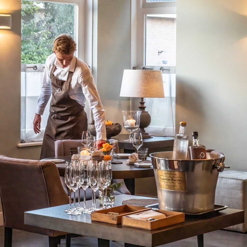 Lichte eetzaal met gedekte tafels en een medewerker die de ruimte voorbereidt — Pieters Restaurant