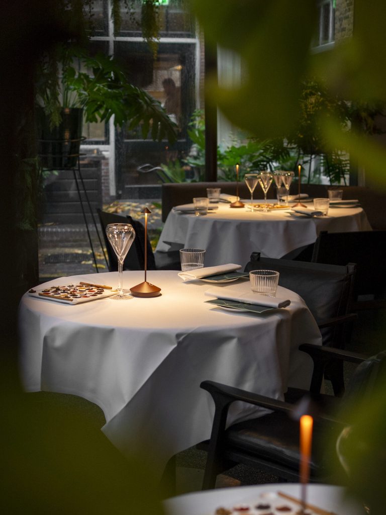 Gedekte ronde restauranttafels met wit tafellinnen — LIZZ