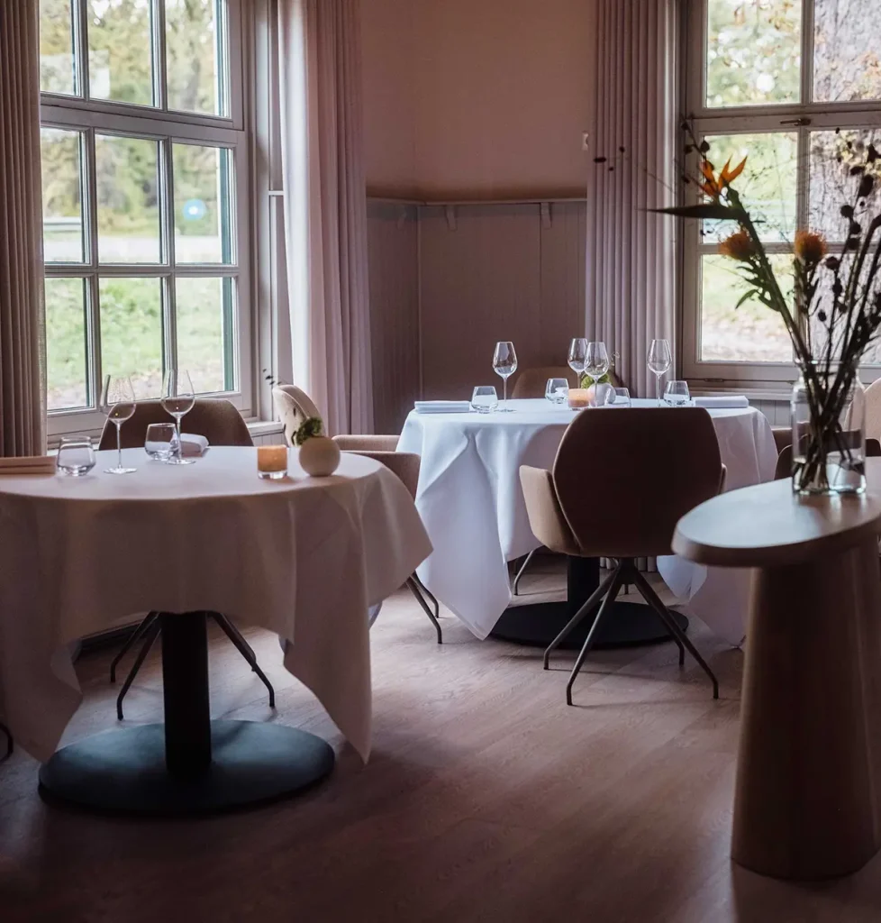 Gedekte tafels bij hoge ramen in het restaurant — Restaurant De Cuijt