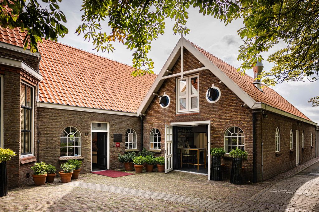Bakstenen restaurantgebouw met rode pannendaken en entree onder een puntgevel — 't Ganzenest
