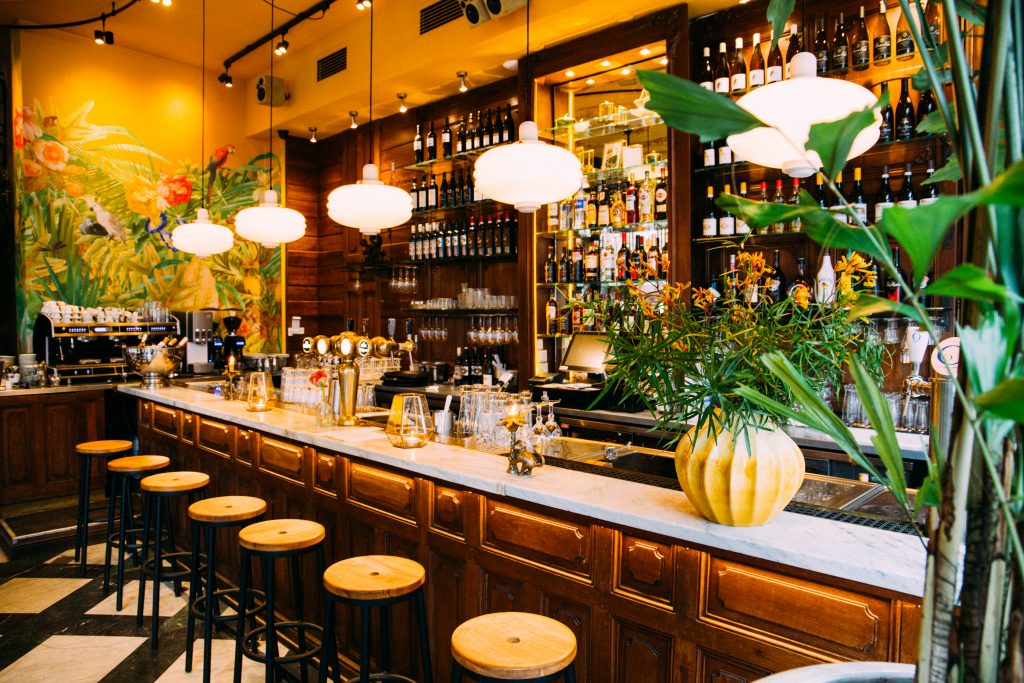 Kleurrijk barinterieur met planten en barkrukken — Café Samabe