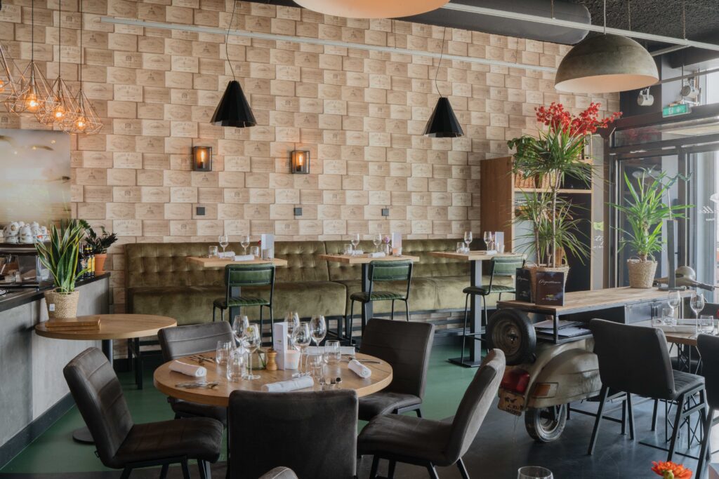 Bistro-interieur met ronde tafels, hanglampen en een bakstenen wand — Bistro De Ertepeller