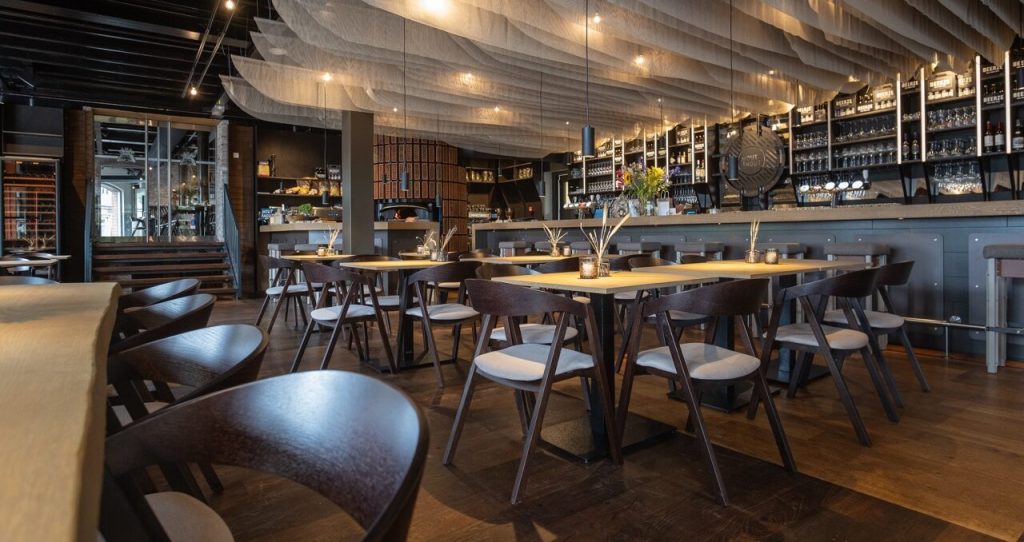 Restaurantinterieur met donkere houten stoelen, ronde tafels en bar — MOUT & HOUT