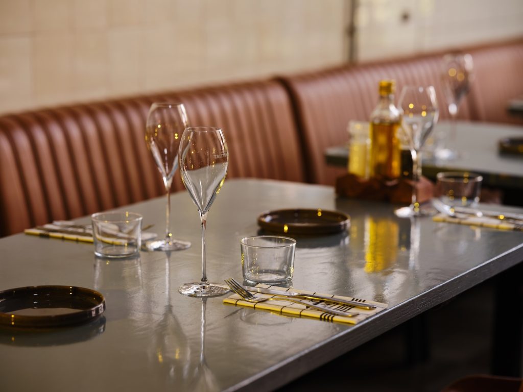 Gedekte restauranttafel bij een lange leren wandbank — Chef aan de Werf