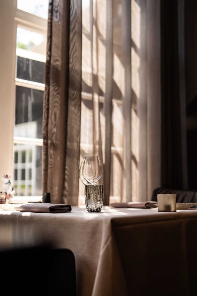 Gedekte tafel met glaswerk bij een raam; staande detailfoto — De Lindenhof