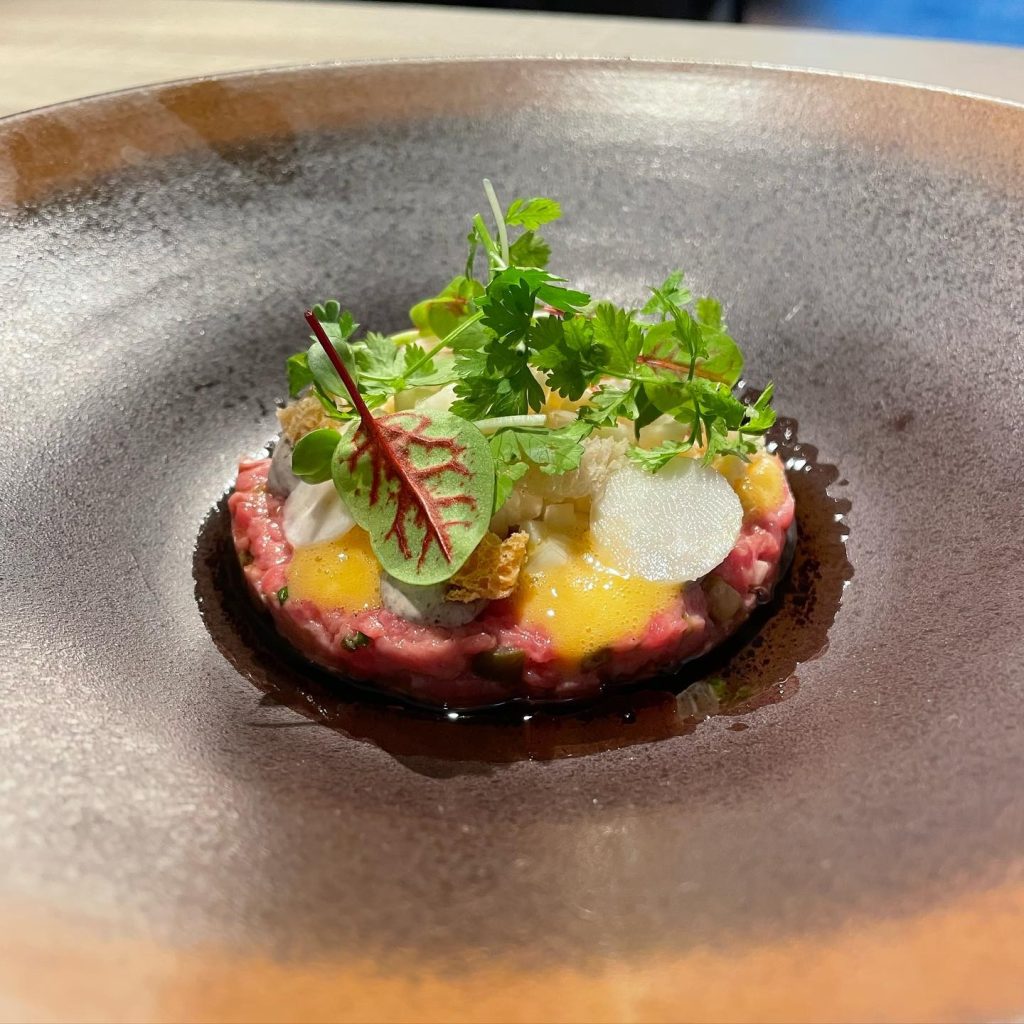 Gerecht op een donker bord met groene garnering — Restaurant Versaen