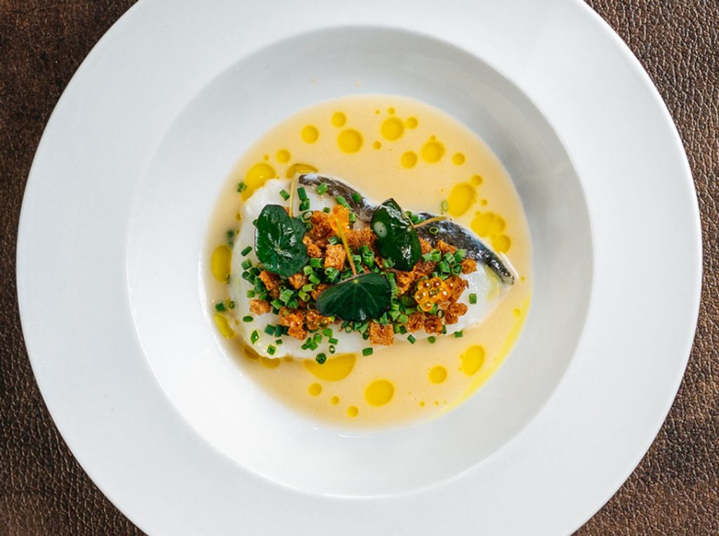 Gerecht op een wit bord met saus en groene garnering — Bovenmeester Diner & Lounge