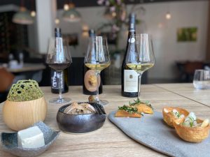Verschillende hapjes op restauranttafel met wijnflessen en glazen op de achtergrond.
