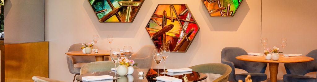 De restaurantzaal met kleurrijke spiegelkunst en gedekte tafels.