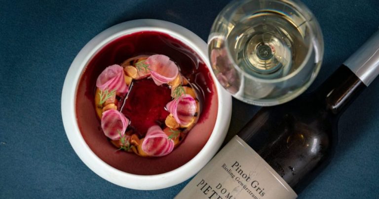 Opmaak van gerecht met bloemen naast wijnfles en glas.
