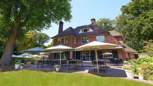 Vrijstaand restaurant met terras en bomen.