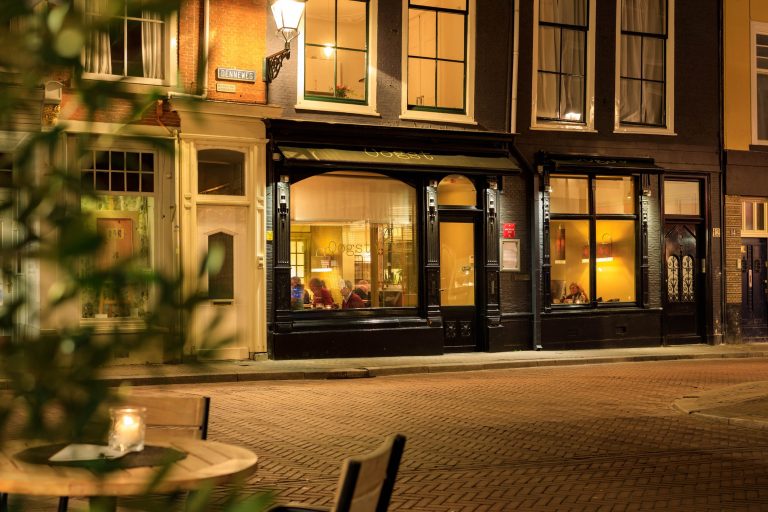 Verlichte restaurantgevel aan de straat in de avond.