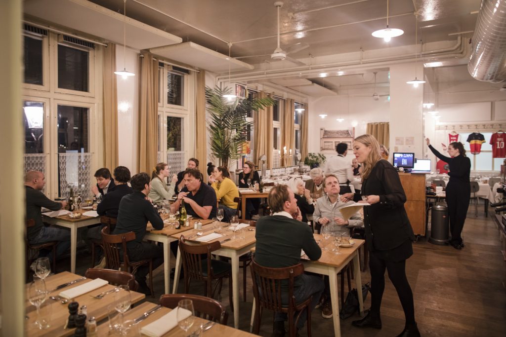 Levendige eetzaal met gasten en bediening.