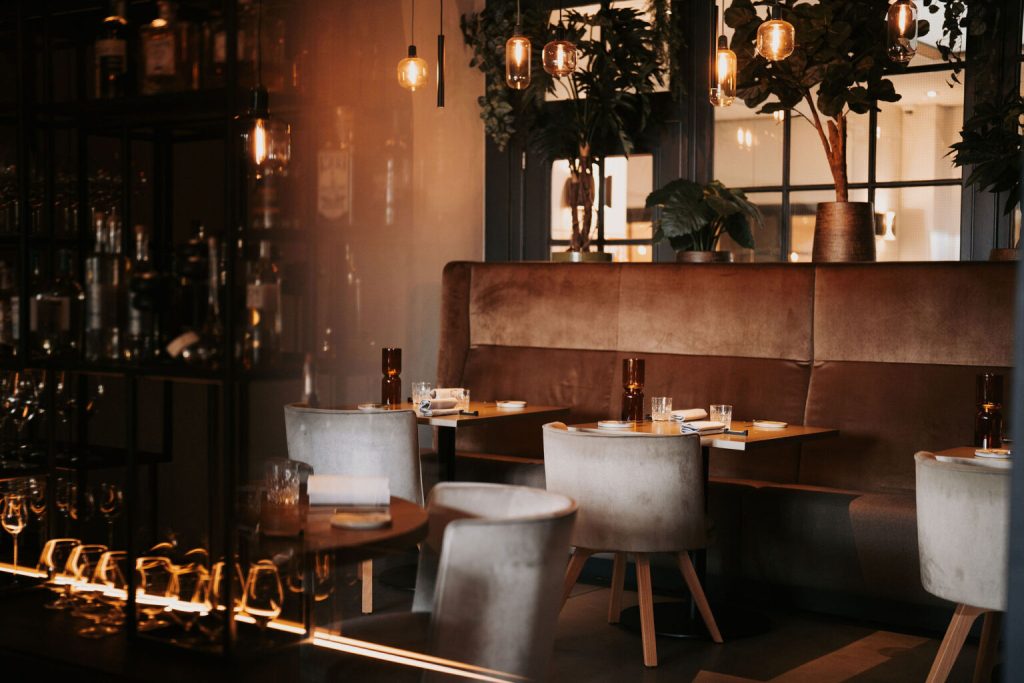 Warm restaurantinterieur met gedekte tafels en bar.