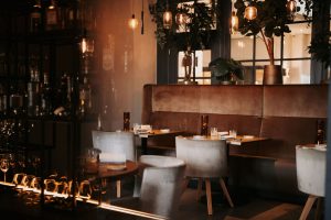 Warm restaurantinterieur met gedekte tafels en bar.