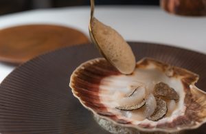 Gerecht in een schelp wordt met saus afgewerkt.