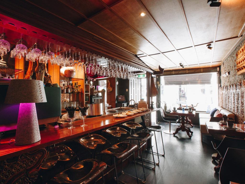 Thaise restaurantzaal met bar en warm rood interieur.