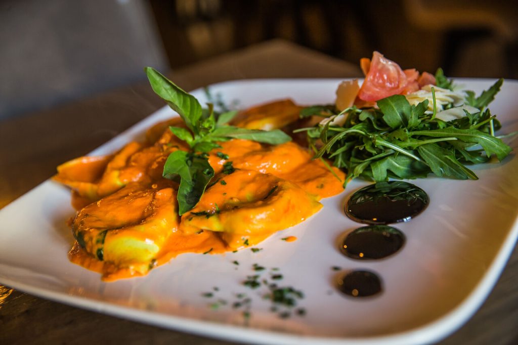 Pasta met saus en groene garnering op een wit bord.