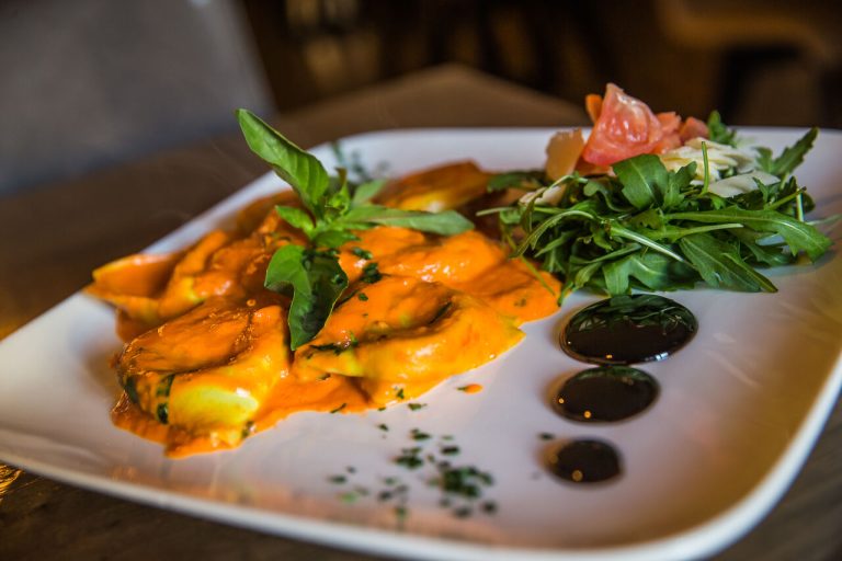Pasta met saus en groene garnering op een wit bord.