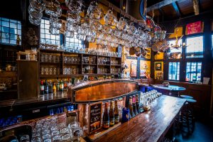Rijk ingerichte houten bar met hangende glazen.