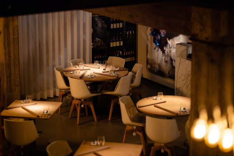 Warm verlichte eetzaal met ronde gedekte tafels.