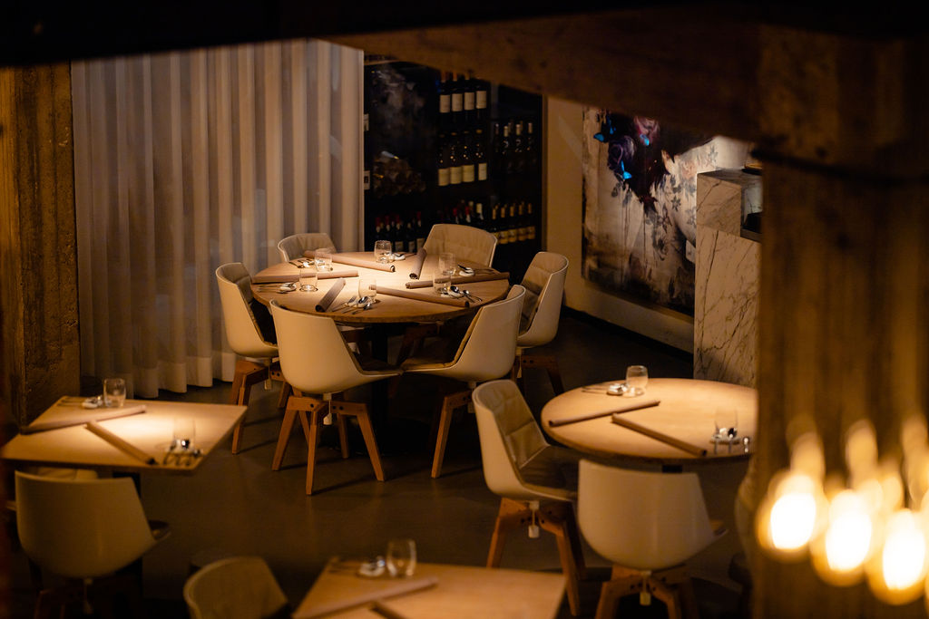 Warm verlichte eetzaal met ronde gedekte tafels.