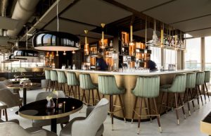 Skybarinterieur met ronde bar en groene barkrukken.