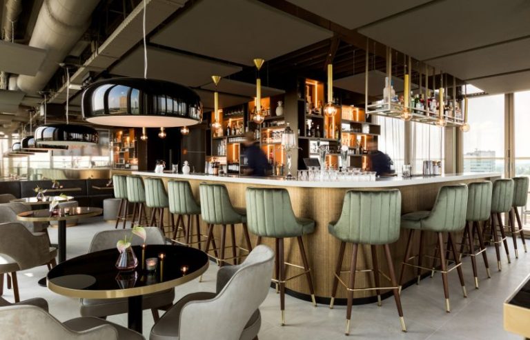 Skybarinterieur met ronde bar en groene barkrukken.