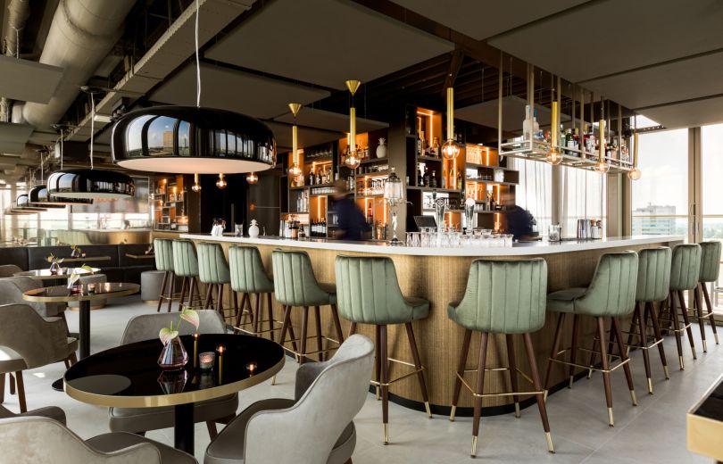 Skybarinterieur met ronde bar en groene barkrukken.