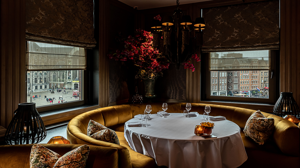 Rijk gedecoreerde eetzaal met ronde tafel en uitzicht op Amsterdam.