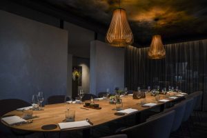 Private-diningruimte met lange gedekte tafel en hanglampen.