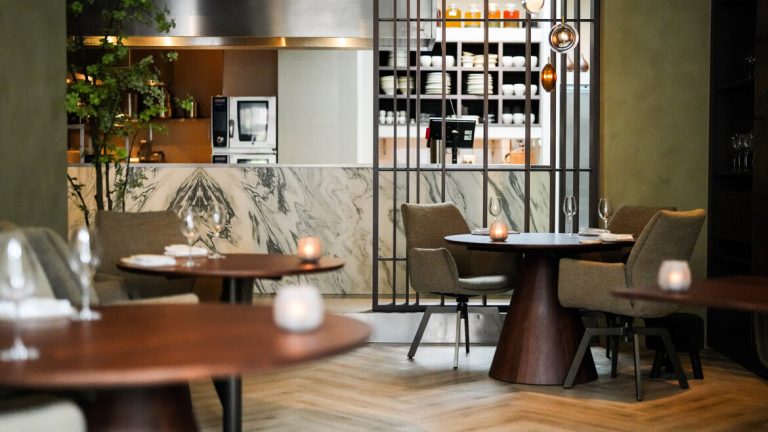 Restauranttafels, stoelen en open bar/keuken.