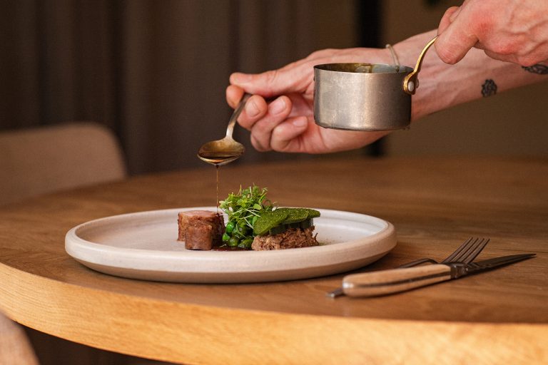 Aan tafel wordt saus over een gerecht geschonken.
