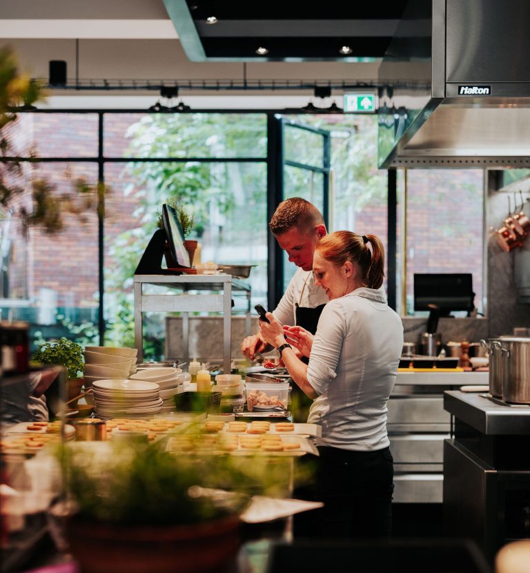 Inkijk in de open restaurantkeuken met medewerkers aan het werk.
