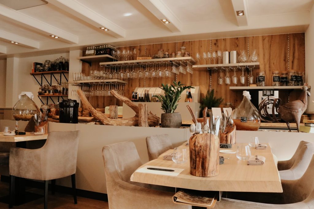Lichte restaurantzaal met open bar, houten wandbekleding en gedekte tafels.
