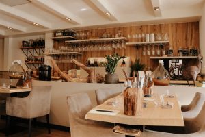 Lichte restaurantzaal met open bar, houten wandbekleding en gedekte tafels.