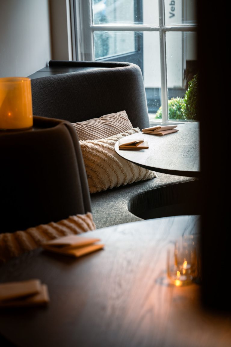 Restauranttafels en zachte zitbank bij een raam.