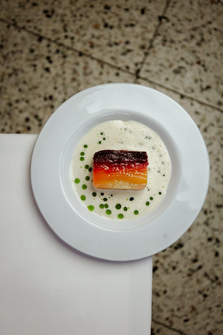 Visgerecht in lichte saus op een rond wit bord.