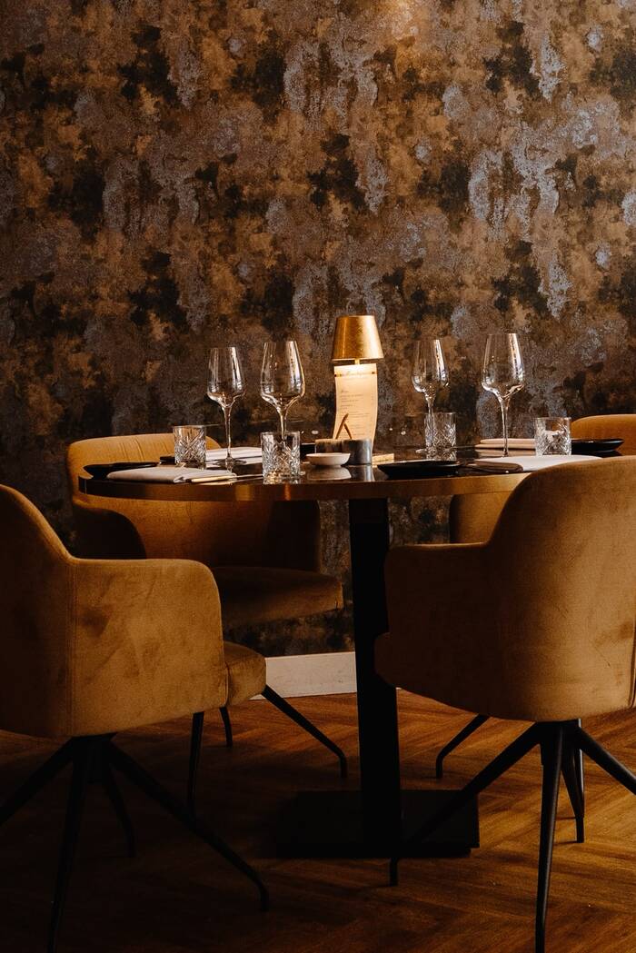 Tafel met gele stoelen bij een bloemenwand.