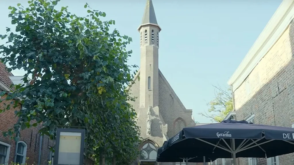 Kerkgebouw en restaurantterras overdag.