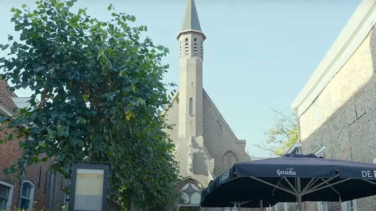 Kerkgebouw en restaurantterras overdag.