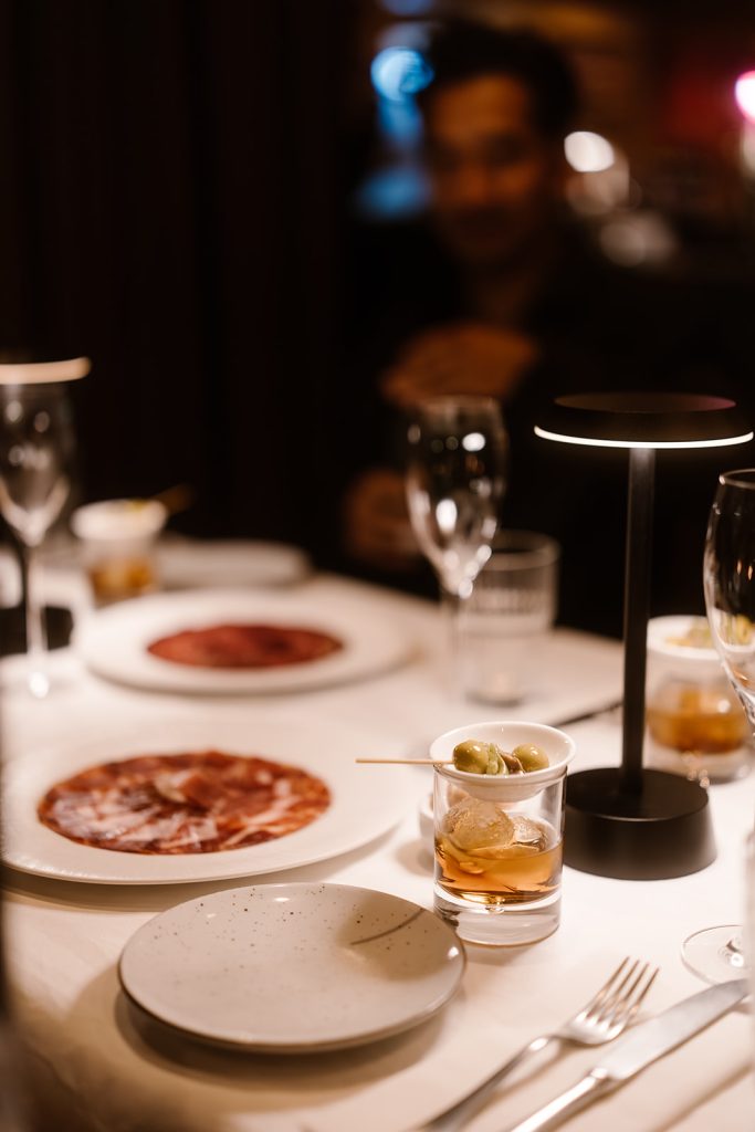 Gedekte restauranttafel met Spaanse gerechtjes en glazen.
