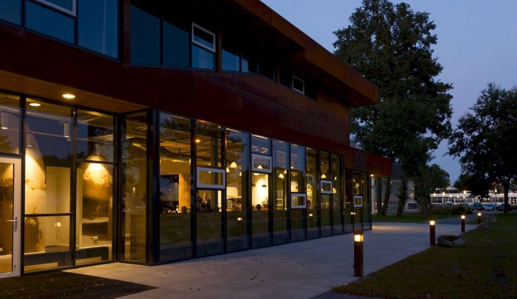 Restaurantgevel met grote ramen in de avond.