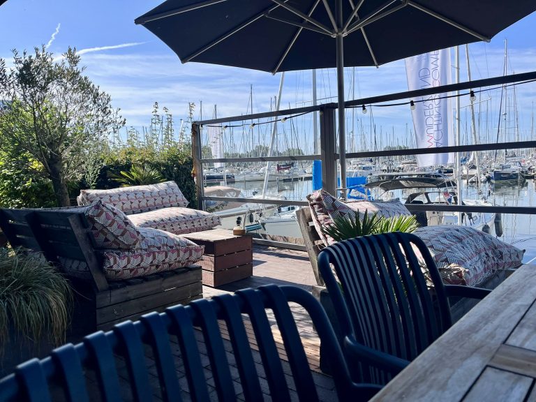 Loungeterras met parasol en zicht op de jachthaven.