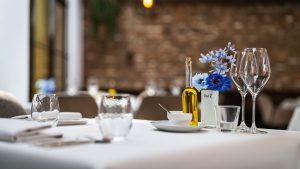 Close-up van gedekte restauranttafel met bloemen, glazen en tafellinnen.