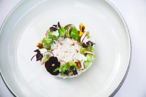 Verfijnd gerecht met groene garnering op wit bord.