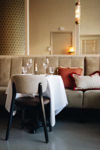 Restauranttafel bij een gecapitonneerde zitbank en rustige lichte wand.