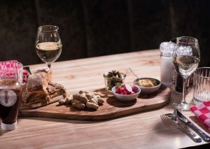Broodplank met smeersels en wijnglazen op een bistrotafel.