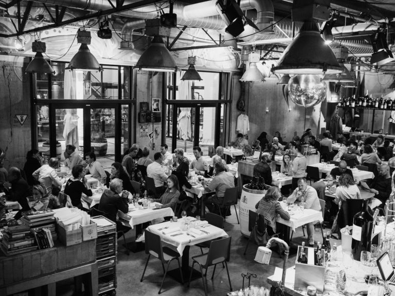 Zwart-witfoto van de industriële eetzaal met gasten aan tafels.